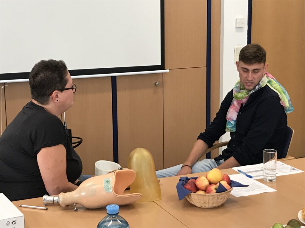Two people having a discussion. Prosthesis parts are in front of them on a table.