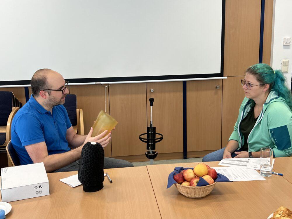 A man holding part of a prosthesis, that he is explaining to another woman.